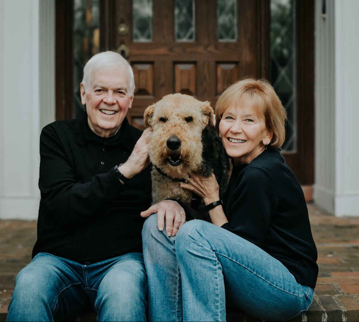 Founders of toby bar sitting on steps with their dog in front of a house.